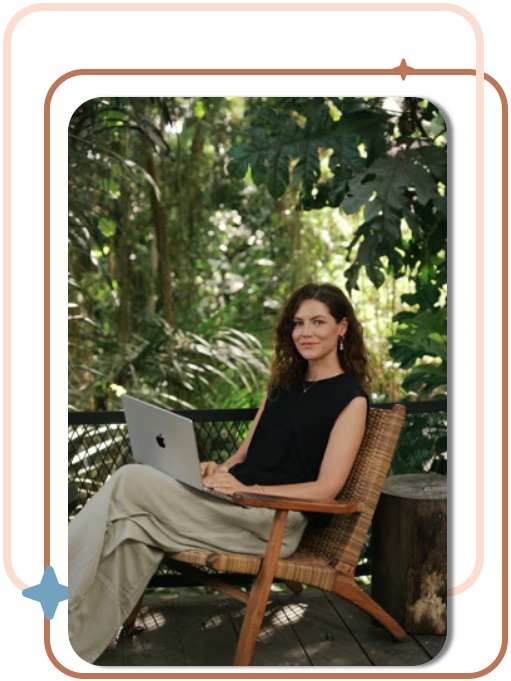 Tiffany, True Tally Bookkeeping founder, working on her laptop in a tropical garden setting
